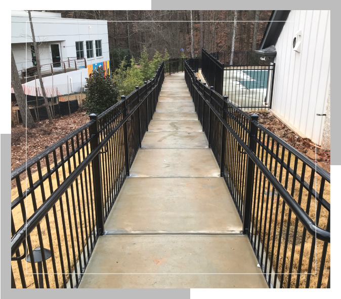 A walkway with metal railings leading to the side of a house.