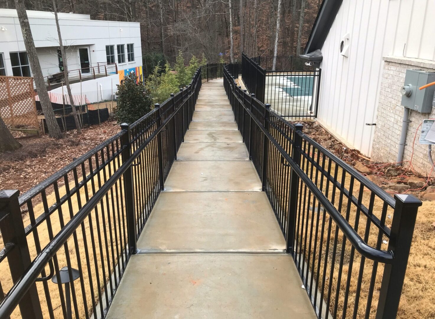 A walkway with metal railings leading to the side of a house.